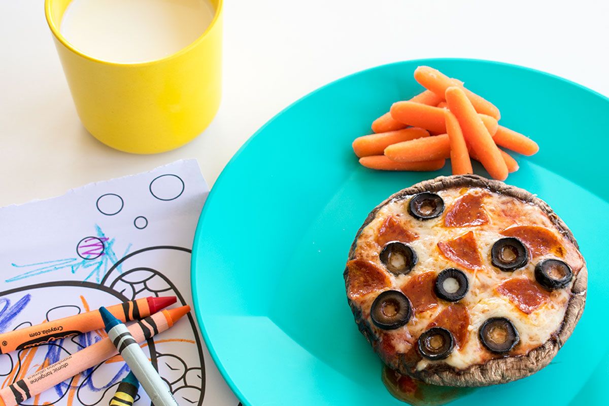 mini mushroom pizza round with carrot sticks, crayons, and milk